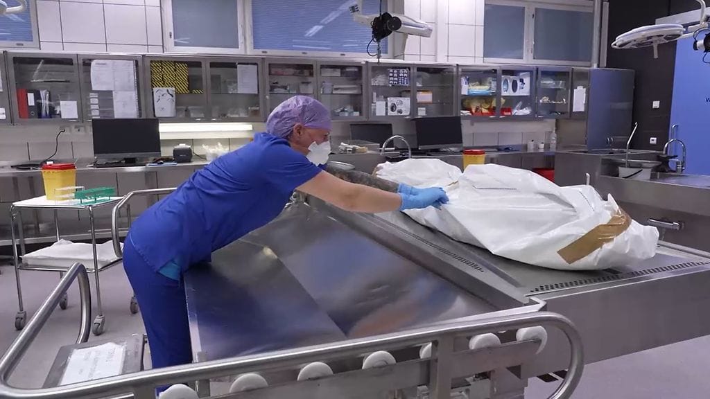 Monesti kuoleman jälkeiset muutokset vainajassa ovat edenneet pitkälle, ennen kuin hän päätyy oikeuslääkärin pöydälle. Kuvassa obduktioteknikko Johanna Varheenmaa siirtää hyväkuntoista vainajaa avauspöydältä kuljetuskärryyn.