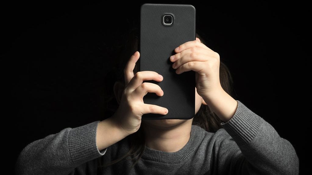 lapsi tuijottaa älypuhelinta