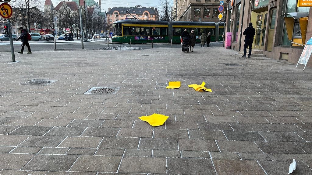 Ateneumin sotku keltaista paperia jalkakäytävällä