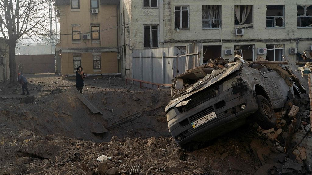 Nainen katsoi iskun aiheuttamaa kraateria Kiovassa 12. helmikuuta 2025.