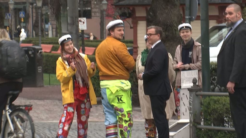 Opiskelijt seisovat värikkäissä haalareissa Esplanadin puistossa pääministeri Petteri Orpon kanssa.