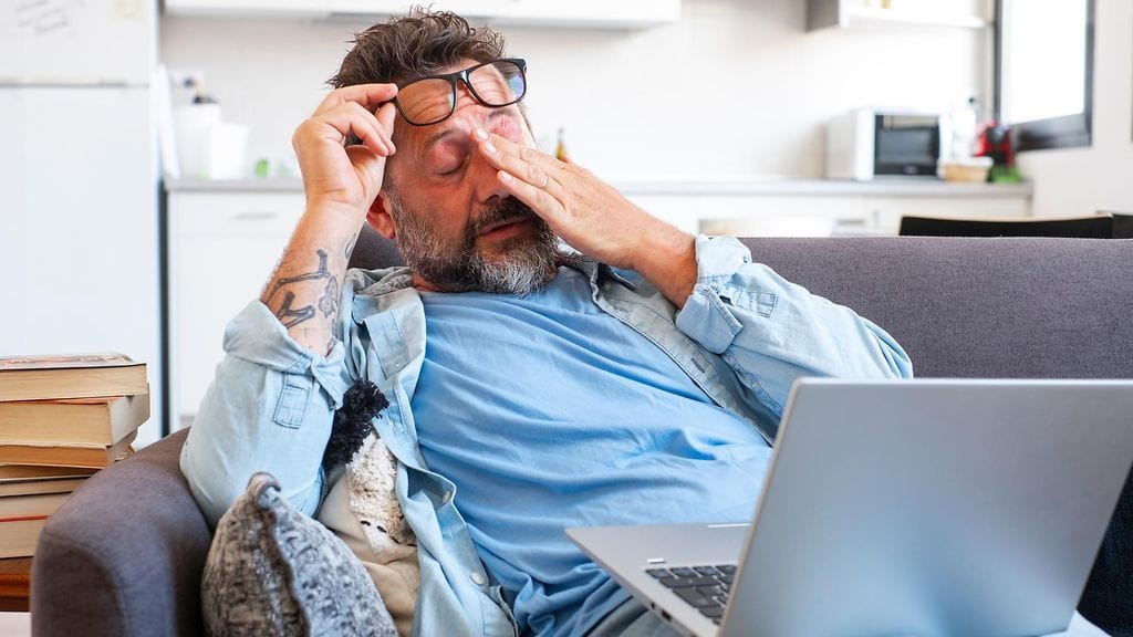 mies sohvalla, väsymys, silmälasit