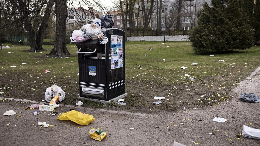 Roska-astia pullollaan Kaivopuistossa, maassa runsaasti roskia.