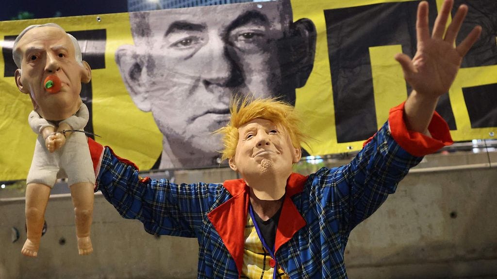 Mielenosoittajalla kasvoillaan Yhdysvaltain presidenttiä Donald Trumpia esittävä naamio ja mukanaan nukke, jossa on Israelin pääministeriä Benjamin Netanjahua esittävä naamio Tel Avivissa lauantaina.