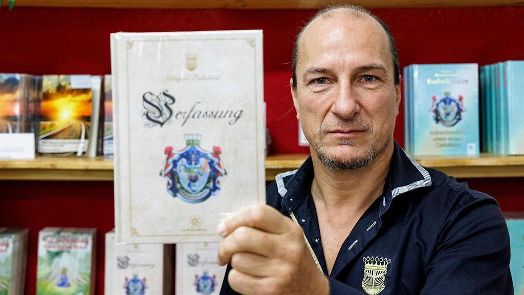 Koenigreich Deutschland -johtaja ja Saksan kuninkaaksi julistautunut Peter Fitzek poseerasi "valtakunnan perustuslain" kanssa Wittenbergissä Itä-Saksassa 23. lokakuuta 2023.