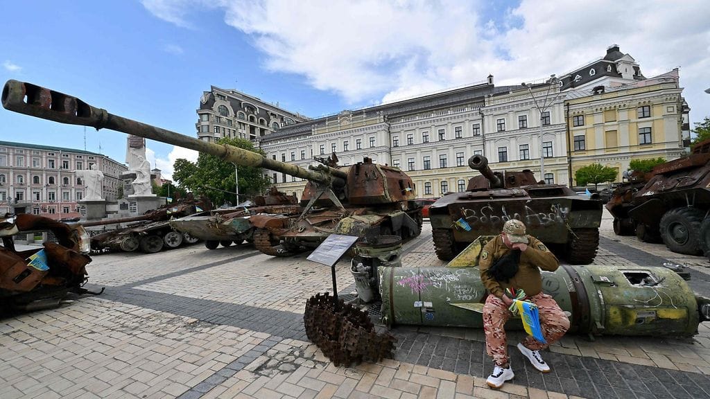 Mies myi Ukrainan lippuja istuessaan ohjuksen päällä Venäjän tuhottua sotakalustoa esittelevässä ulkoilmamuseossa Kiovassa 19. toukokuuta 2025.