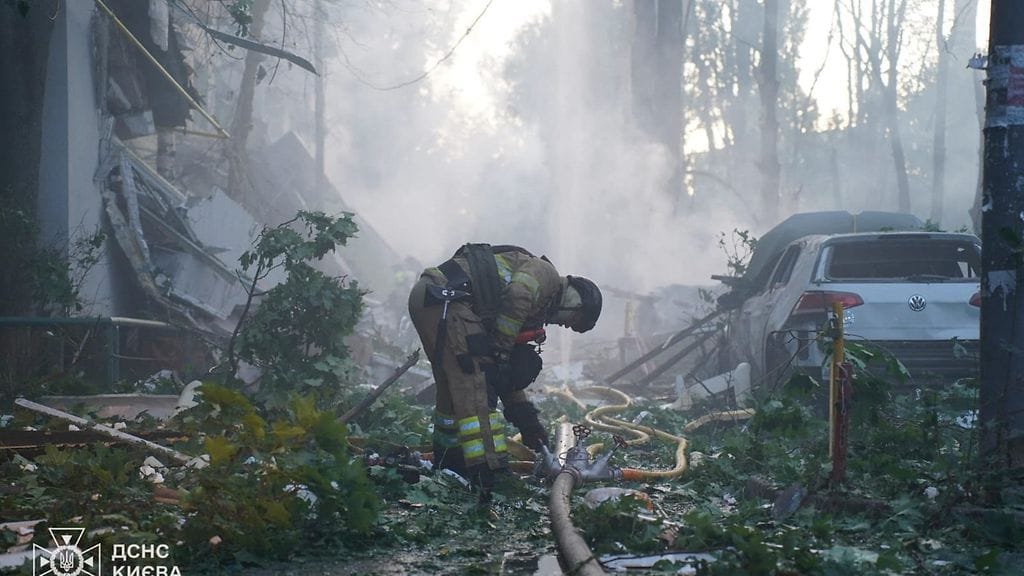Ukrainan hätäkeskuslaitoksen välittämä kuva näyttää, kuinka palomies työskentelee asuinrakennuksen ulkopuolella iskujen jälkeen.