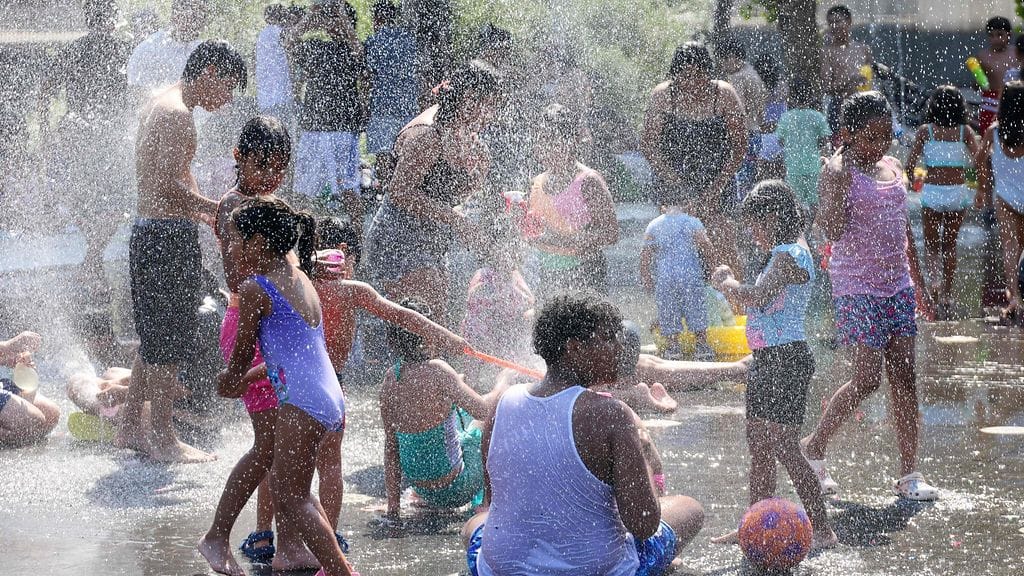 Ihmiset viilentyvät suihkulähteiden luona Madridissa.