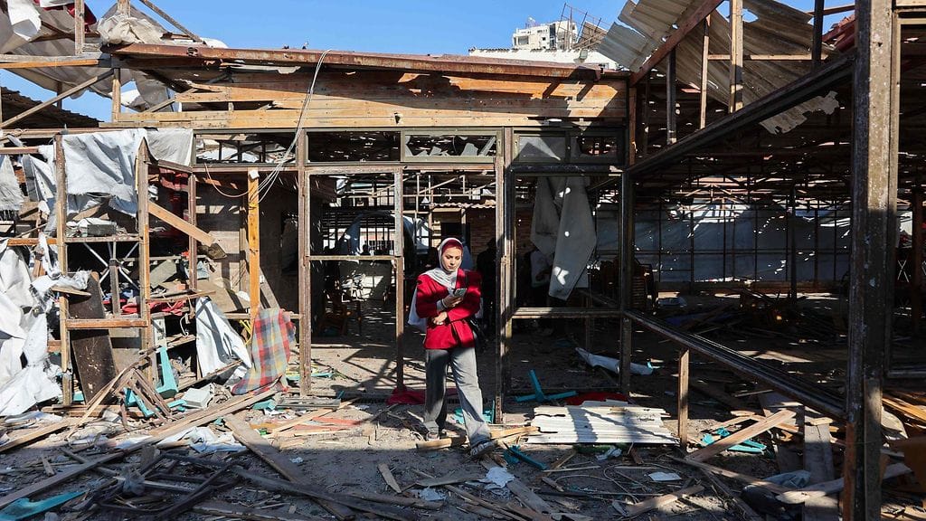 Palestiinalaisnainen kävelee kahvilan raunioissa Gazassa. Iskussa kuoli yli 20 ihmistä.