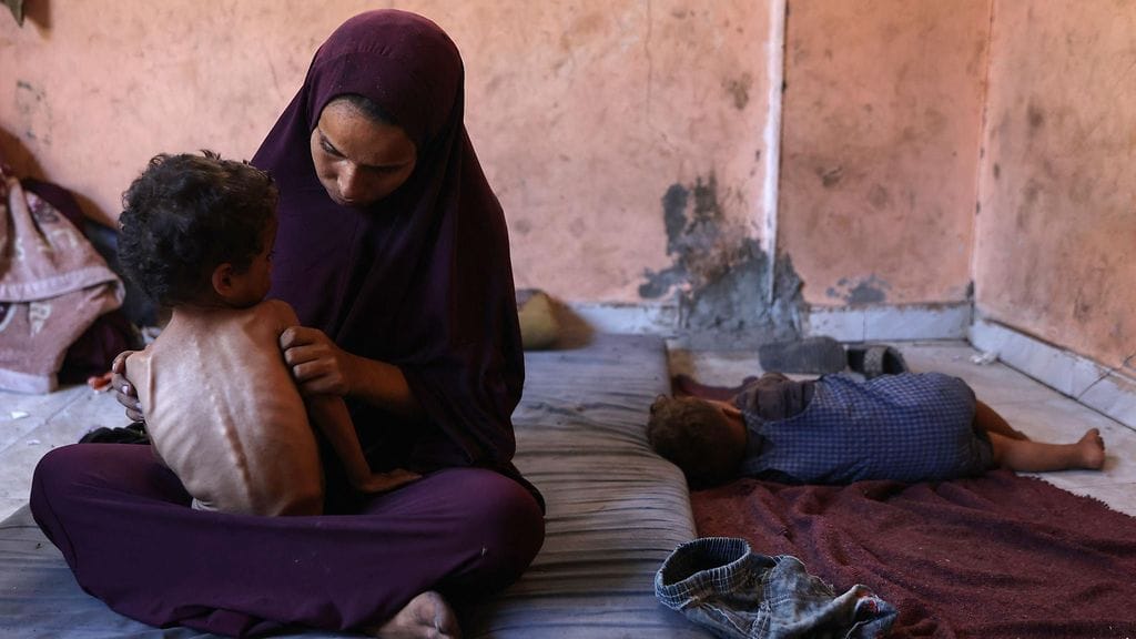Naeema, 30-vuotias palestiinalainen äiti, istuu aliravitun 2-vuotiaan poikansa Yazanin kanssa vahingoittuneessa kodissaan.