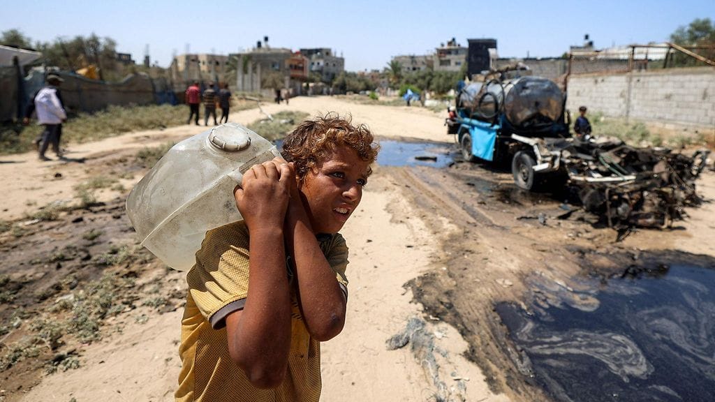 Kuvassa poika kantaa selässään vesikanisteria Nuseiratin pakolaisleirillä Gazan kaistalla 14. heinäkuuta 2025.