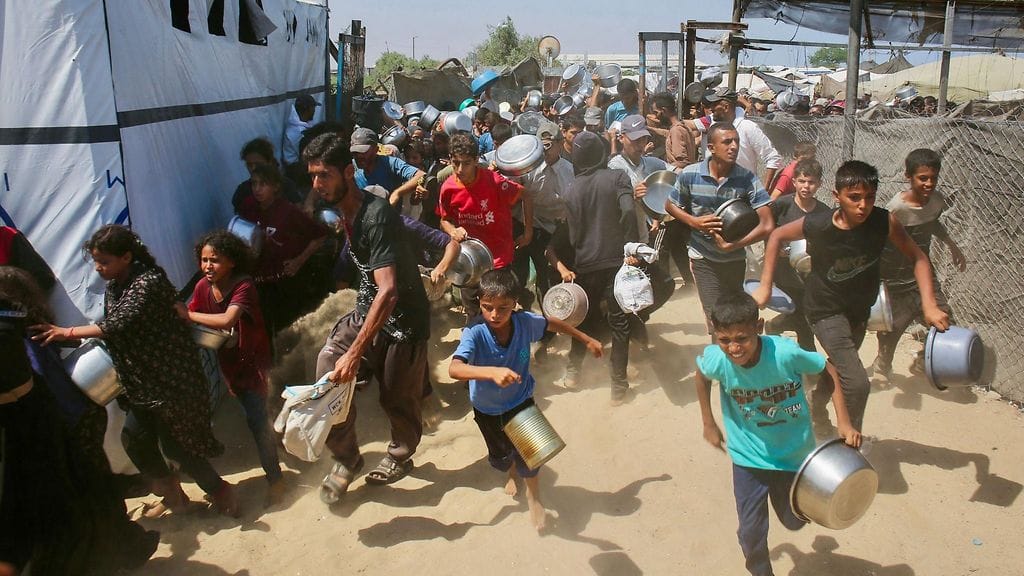 Palestiinalaiset lapset hakivat ruokaa hyväntekeväisyyskeittiöstä Mawasin alueella Khan Yunisissa Gazan eteläosassa 22. heinäkuuta 2025.