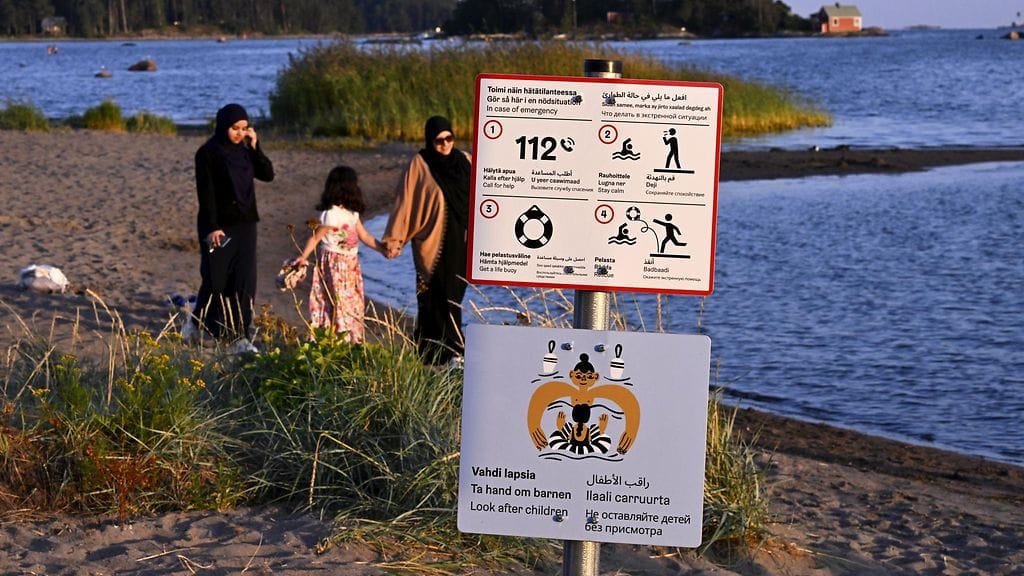 Usealla eri kielellä hätätilanteessa toimimisesta ohjeistava sekä lapsien vahtimisesta muistuttava kyltti Kallahden uimarannalla Helsingissä.