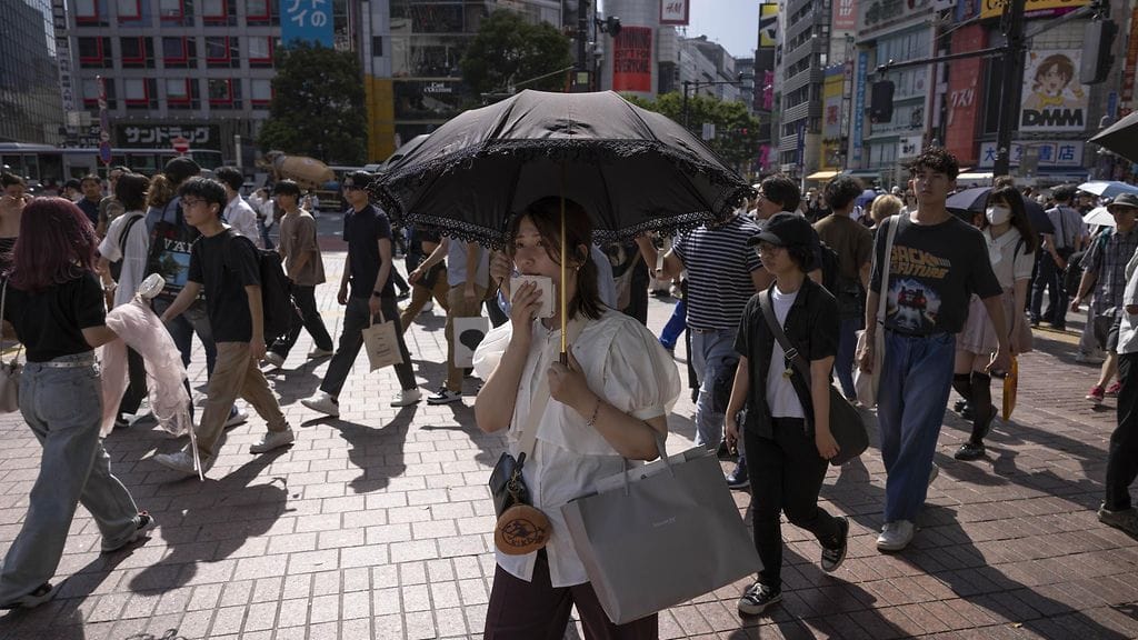 Nainen suojautuu helteeltä Japanin pääkaupungissa Tokiossa.