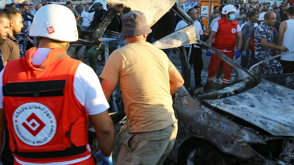 Libanonin poliisi ja pelastushenkilöstön jäsen tarkastavat autoa, joka oli israelilaisten iskun kohteena.