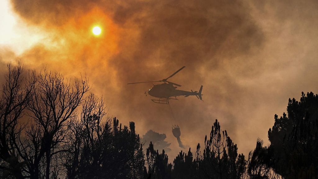 Kuvassa sammutushelikopteri pudottaa vettä palojen sammuttamiseksi.