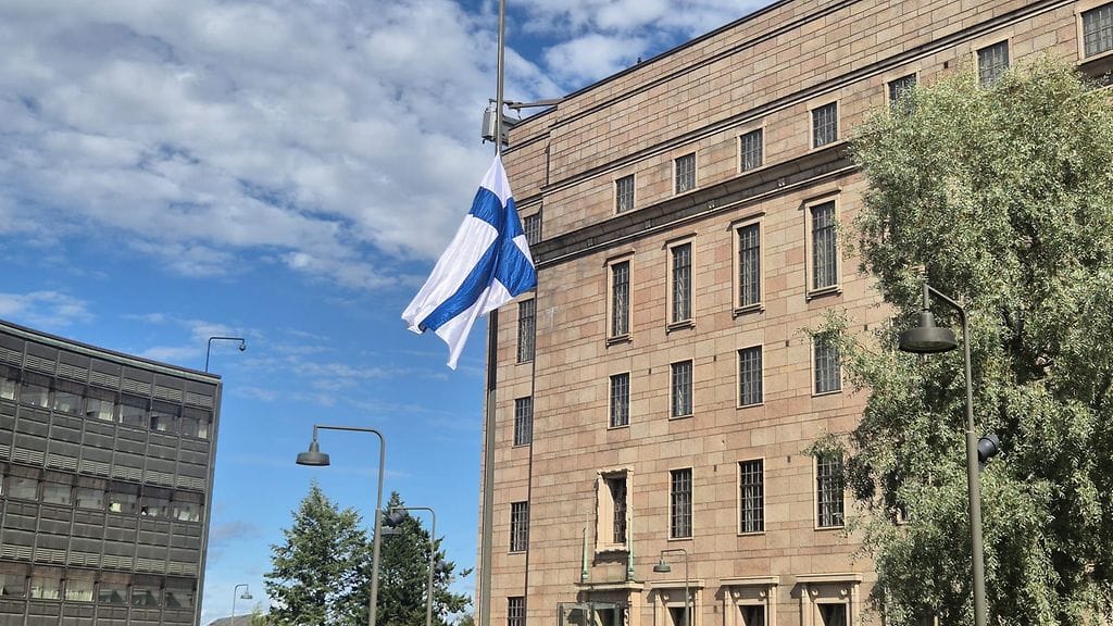 Suomen lippu on puolisalossa eduskuntatalon edustalla.