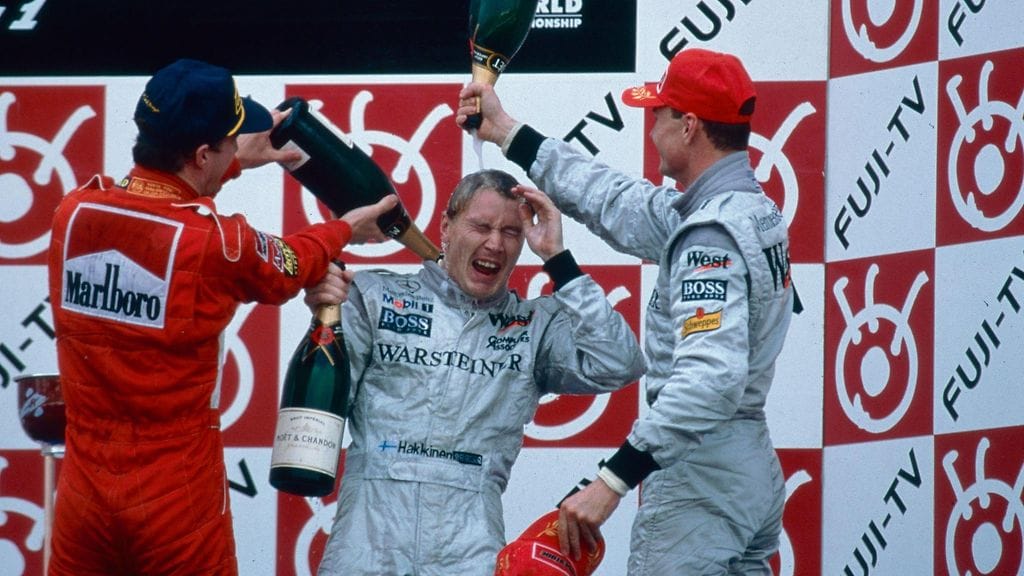 McLarenin Mika Häkkinen juhli Japanin GP:n voittoa vuonna 1998. Suomalaisen kastelivat tiimitoveri David Coulthard ja Ferrarin Eddie Irvine.
