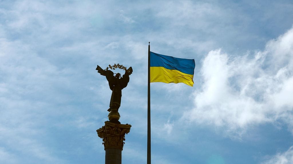 Ukrainan lippu liehuu itsenäisyysmonumentin vieressä Itsenäisyyden aukiolla Kiovan keskustassa.