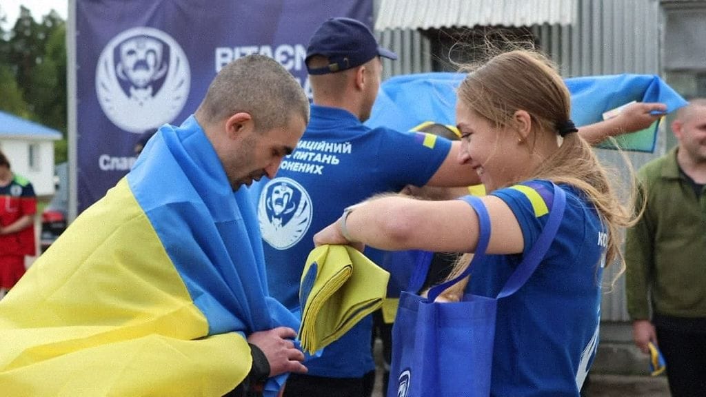 Sotavankien kohtelusta vastaavan koordinaatiokeskuksen julkaisemassa kuvassa työntekijä ojensi Ukrainan kansallislipun ukrainalaiselle sotavangille vankienvaihdon jälkeen Ukrainassa.