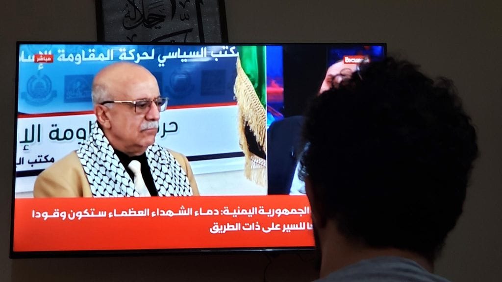 Kuvassa mies katselee televisiosta, kun huthien pääministeri Ahmed Al-Rahawin kuolemasta kerrotaan.