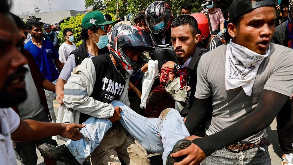 Mielenosoittajat kantoivat haavoittunutta miestä Nepalin pääkaupungissa Kathmandussa.