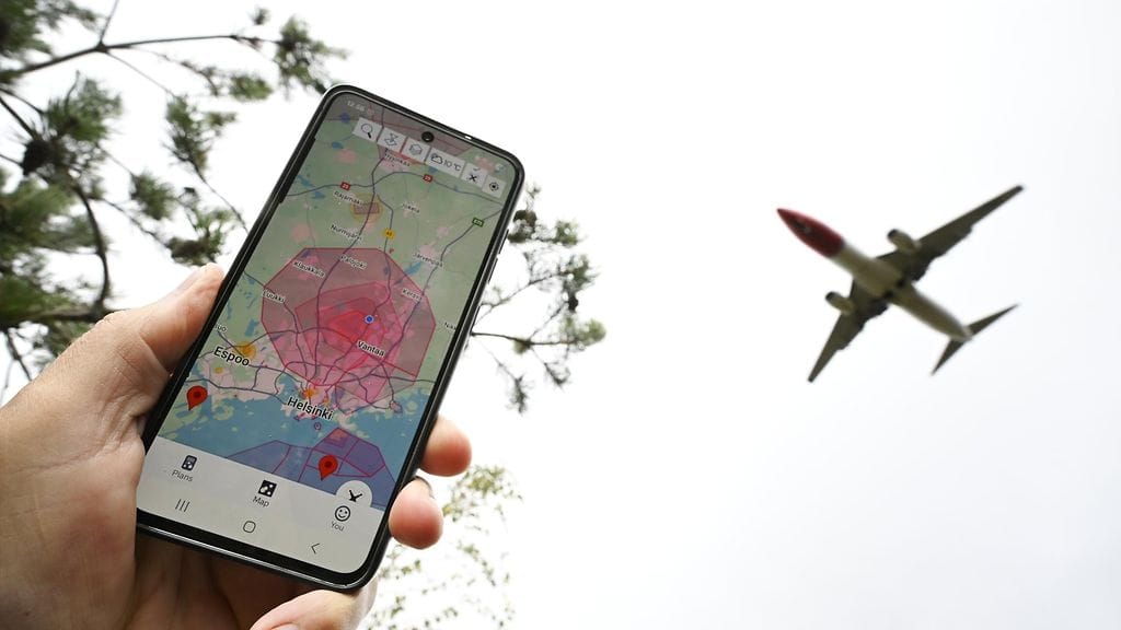 Kuvituskuva. Laskeutuva lentokone ja dronelentokieltoalue kännykän näytöllä Lemminkäisen kalliolla Tuusulassa Helsinki-Vantaan lentiokentän läheisyydessä 23. syyskuuta 2025.