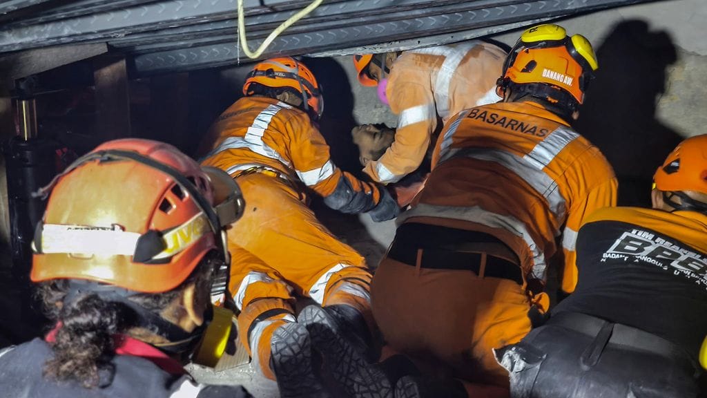 Indonesian viranomaisten jakamassa kuvassa pelastustyöntekijät vetävät eloonjäänyttä turvaan koulun raunioista 1. lokakuuta 2025.