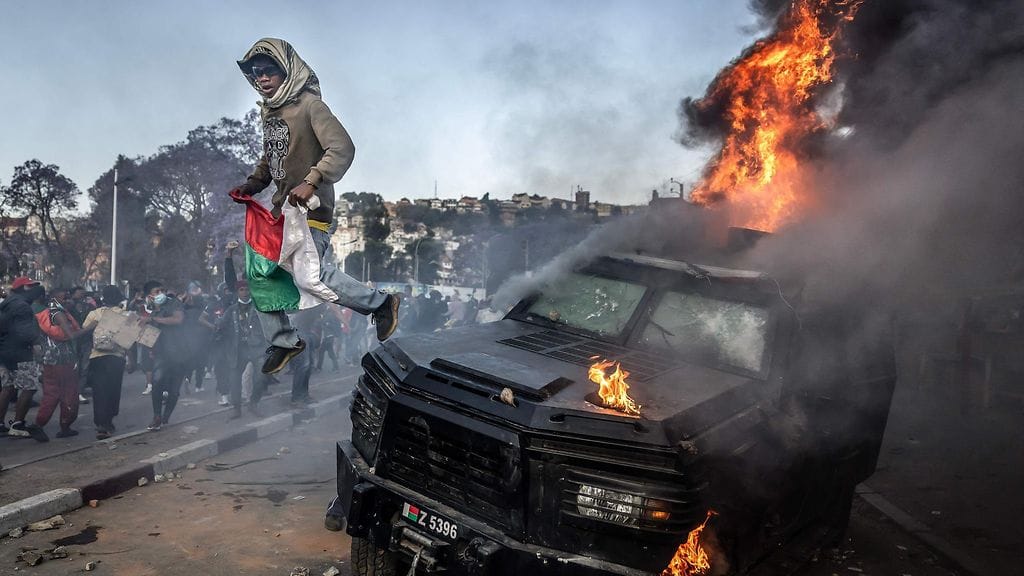 Mielenosoittaja hyppää poltetun santarmien panssariajoneuvon päältä mielenosoituksessa, jossa vaadittiin presidentin eroa Antananarivossa lauantaina.