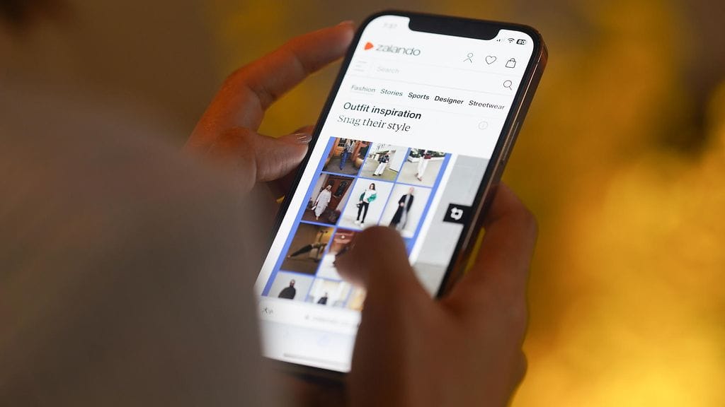 Nainen selaa Zalandon valikoimaa puhelimellaan.