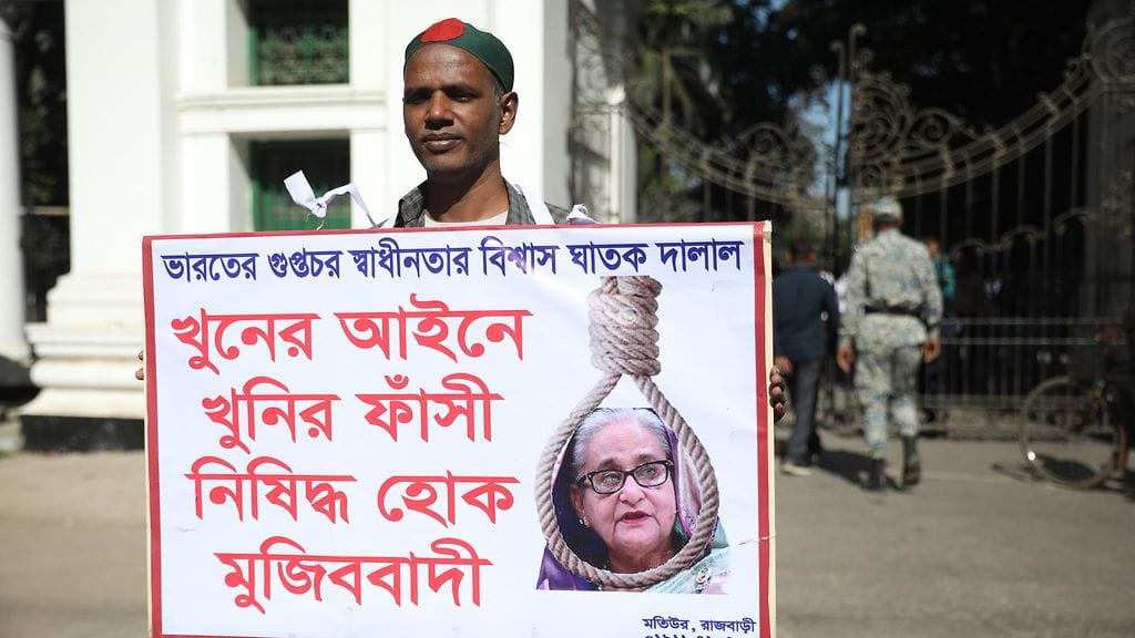 Henkilö pitelemässä kylttiä, jossa vaaditaan entisen pääministerin kuolemaa.