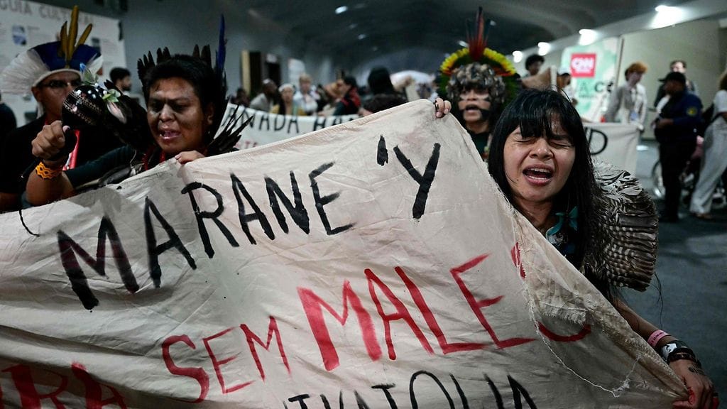 Alkuperäiskansojen johtaja ja ilmastoaktivisti Txai Surui (oikealla) huusi iskulauseita poistuessaan täysistunnosta COP30-ilmastokokouksessa Belémissä Brasiliassa perjantaina.