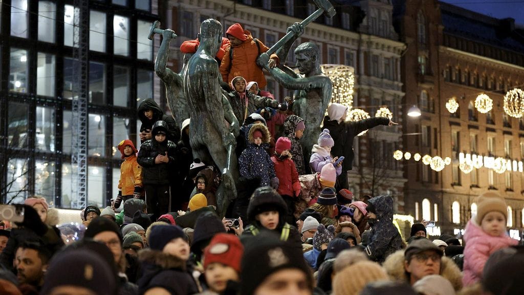 LK 22.11.2025 Yleisöä Kolmen sepän patsaan päällä joulukadun avajaisissa Aleksilla Helsingissä 22. marraskuuta 2025. Paraatikulkue lähti Senaatintorilta ja samalla sytytettiin Aleksanterinkadun jouluvalot.