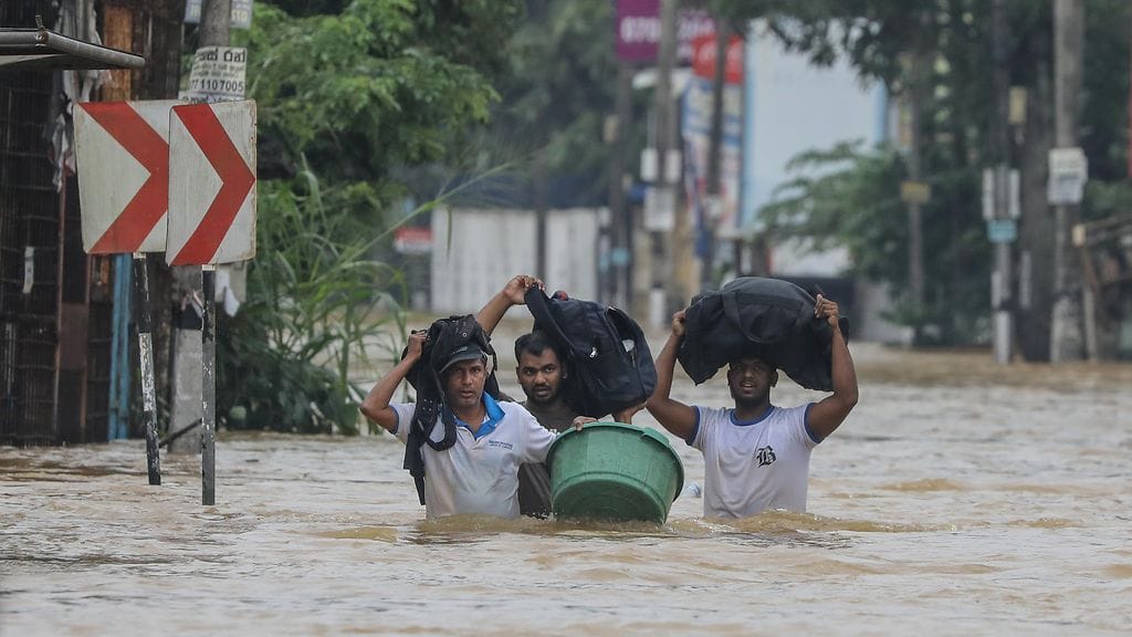 Tulvien uhrit kahlaavat tulvineella tiellä rankkasateen aikana Colombon esikaupungissa Sri Lankassa 29. marraskuuta 2025.