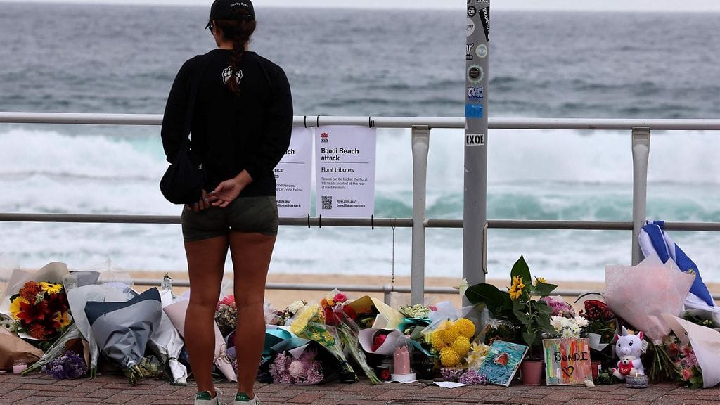 Nainen pysähtyi Bondi Beachille tuotujen muistokukkien äärelle 16. joulukuuta 2025.