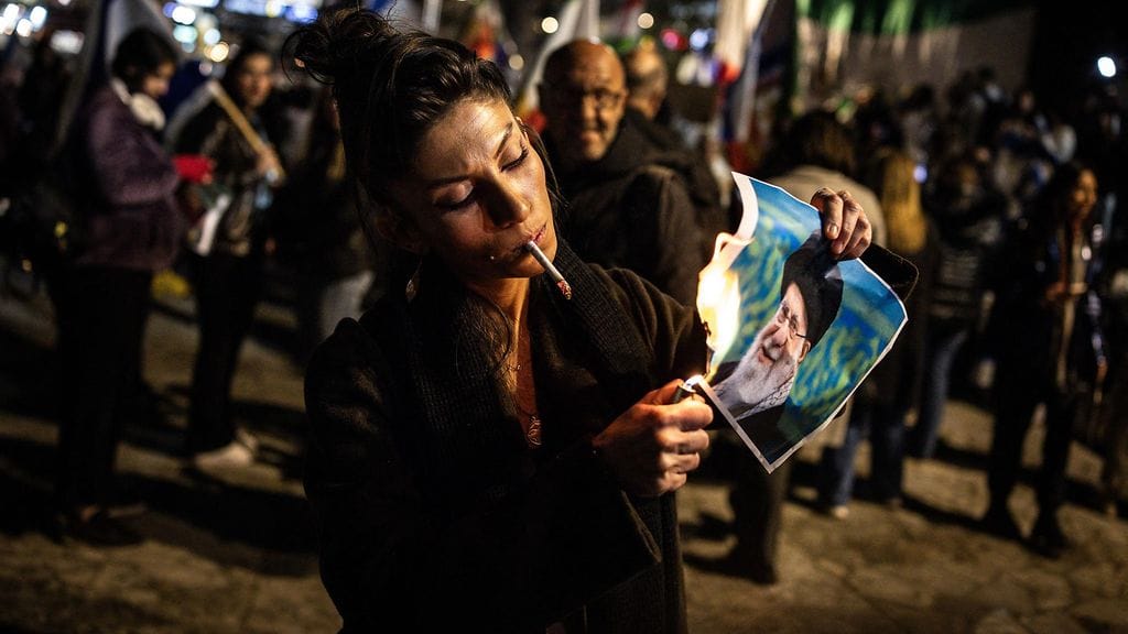 Mielenosoittaja polttaa Iranin ylimmän johtaja Ali Khamenein kuvaa.