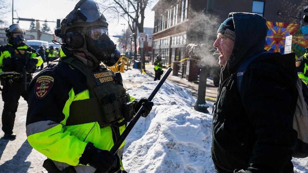 Mies puhuu Minnesotan viranomaisen kanssa, kun mielenosoittajat kokoontuivat paikalle, jossa valtion ja paikallisten viranomaisten mukaan liittovaltion agentit ampuivat ja tappoivat miehen aiemmin aamulla Minneapolisissa, Minnesotassa, 24. tammikuuta.