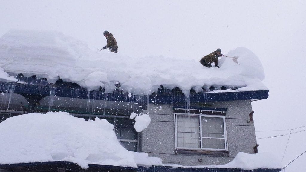 Japanin maavoimien jalkaväkirykmentin sotilaat poistivat lunta Aomorin prefektuurissa. Jatkuva lumisade on haudannut alueita jopa kahden metrin kinoksiin.