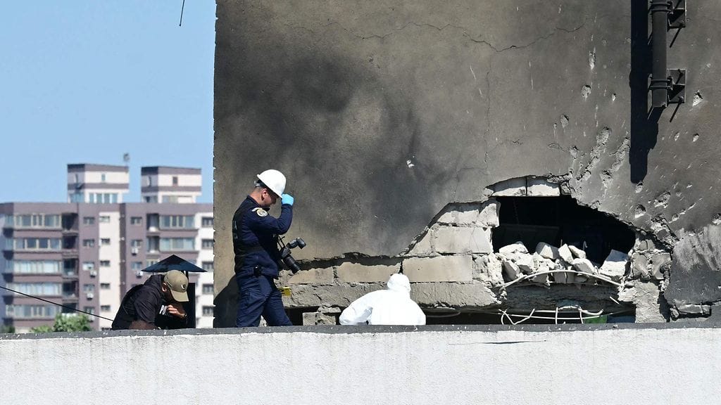 Poliisi ja rikostekniset tutkijat törmäyspaikalla droonista osuman saaneessa kerrostalossa Romanian Galatissa.