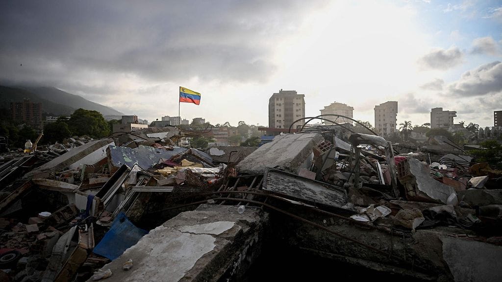 Venezuelan lippu liehui romahtaneen rakennuksen raunioiden päällä Caraballedassa Venezuelassa 27. heinäkuuta 2026, noin kuukausi maanjäristysten jälkeen.