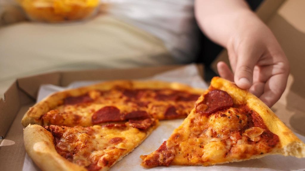 nainen syö sohvalla pizzaa shutterstock