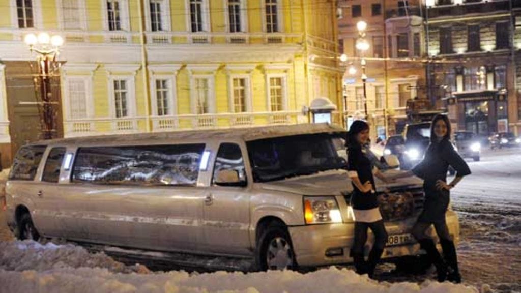 Tytöt poseeraavat pidennetyn limusiinin edessä.